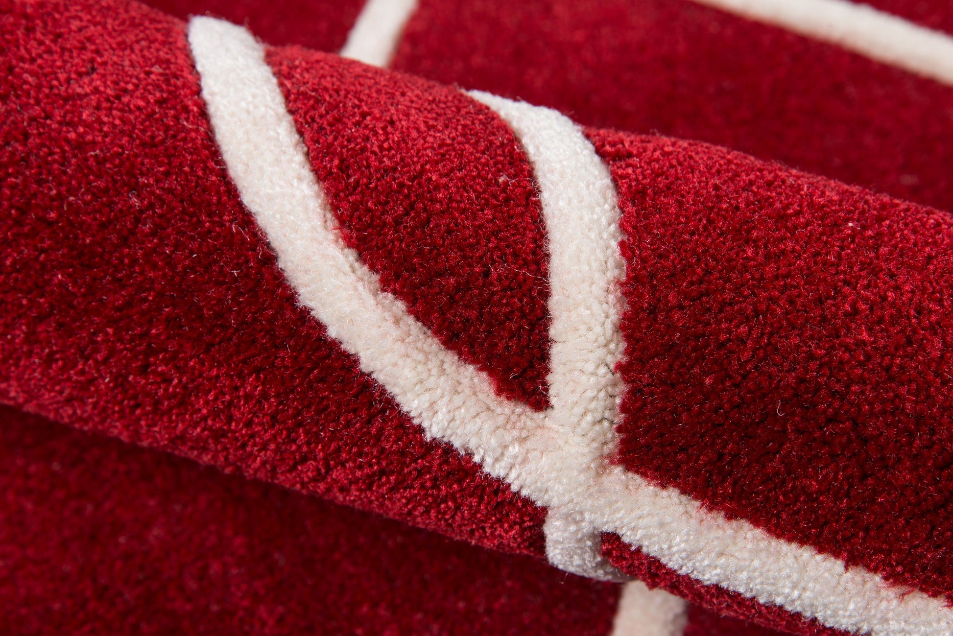 Close-up of a red rug with a white border trim, showing a plush pile texture.