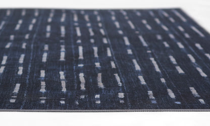 Dark blue woven rug with light gray dashed vertical lines in a modern abstract pattern.