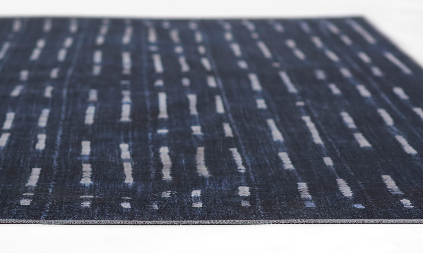 Navy blue flat-weave rug with light gray dash stripes in a modern abstract pattern.