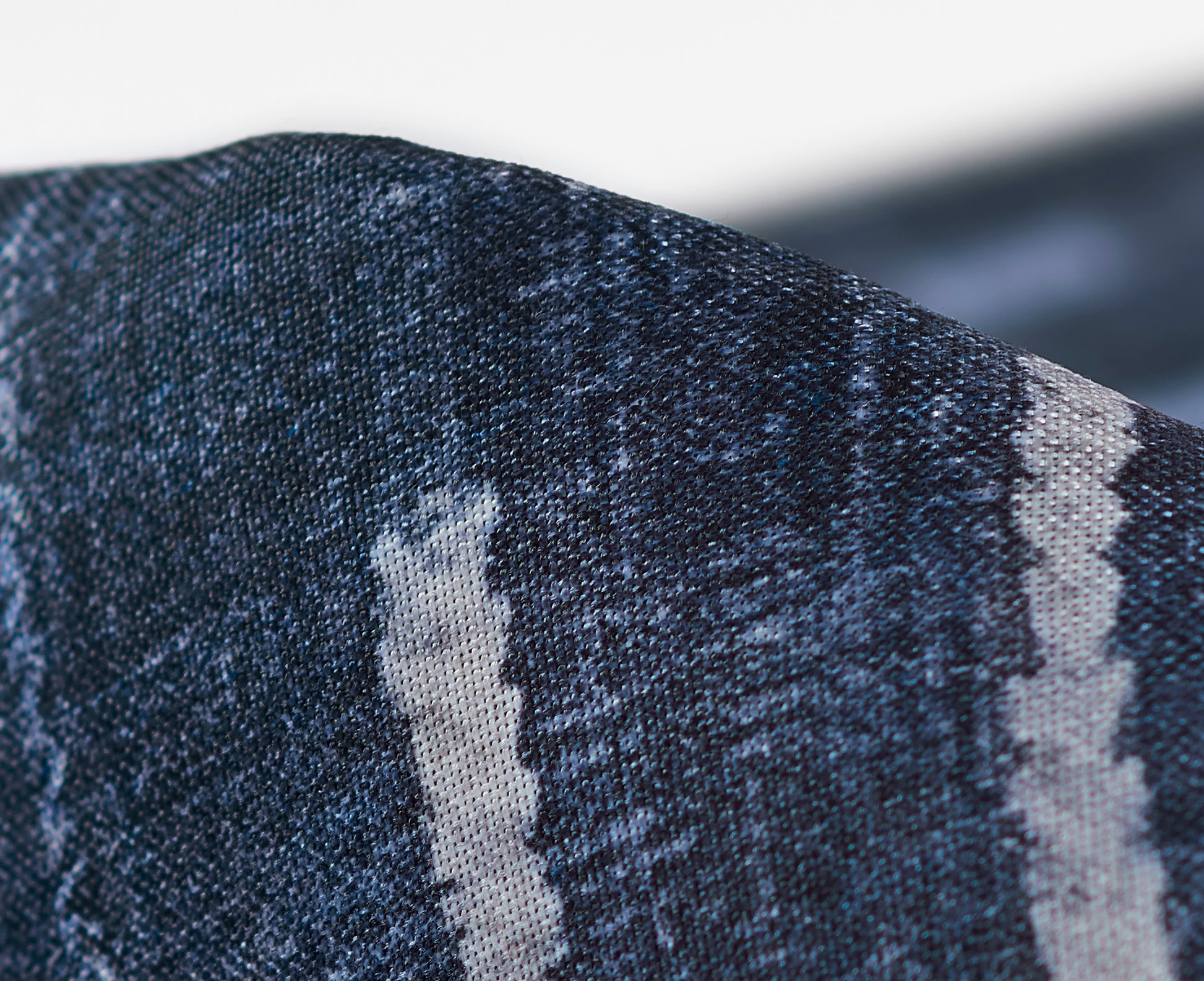 Close-up of dark indigo denim fabric with a light gray vertical stripe and textured weave.