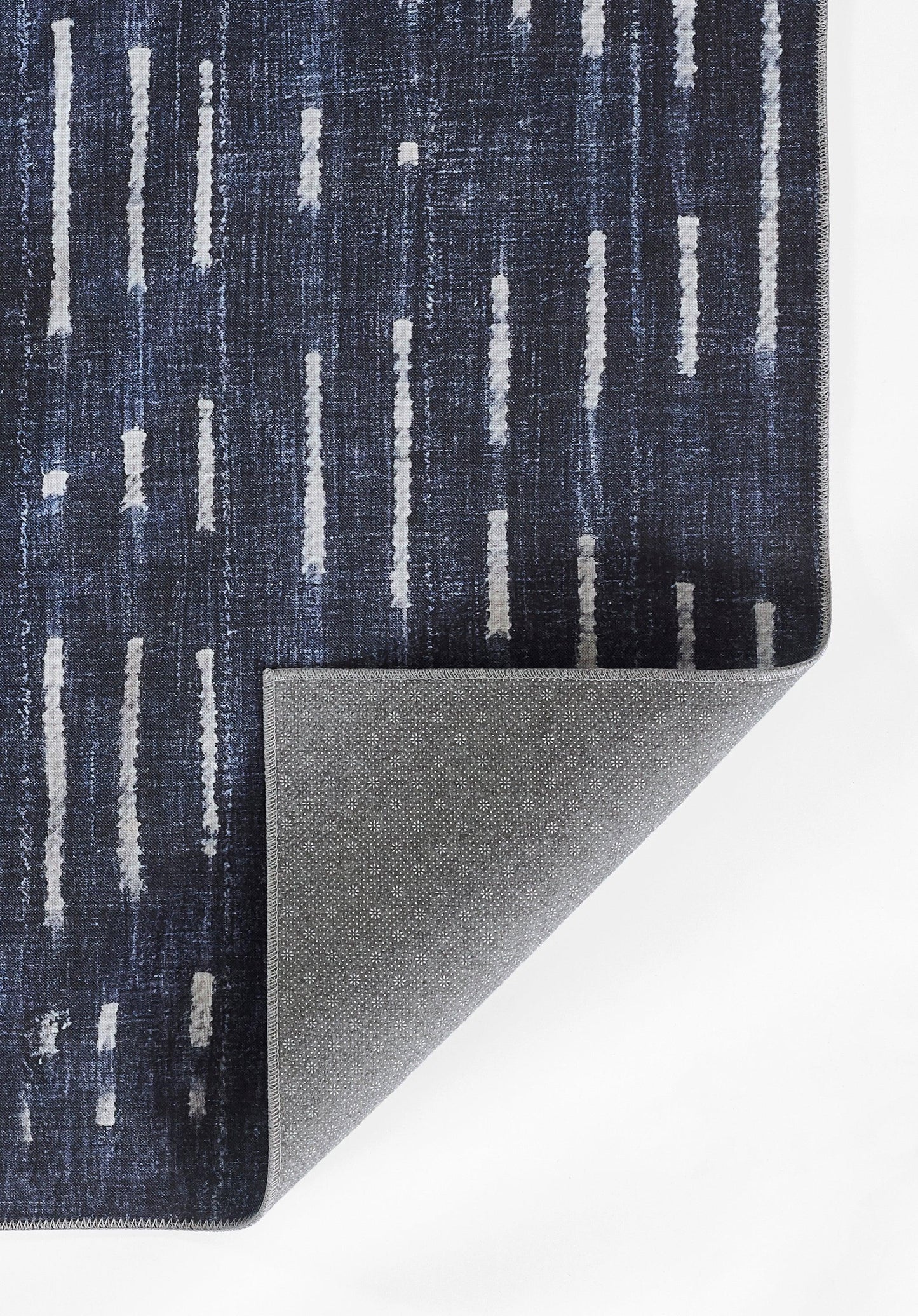 Dark blue woven rug with vertical light-gray streaks; folded corner reveals speckled grey backing.