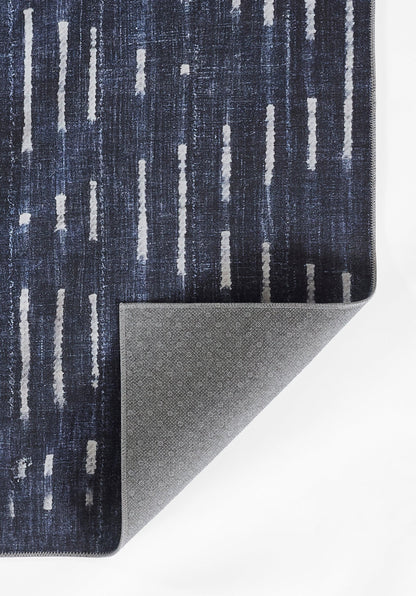 Dark blue woven rug with vertical light-gray streaks; folded corner reveals speckled grey backing.