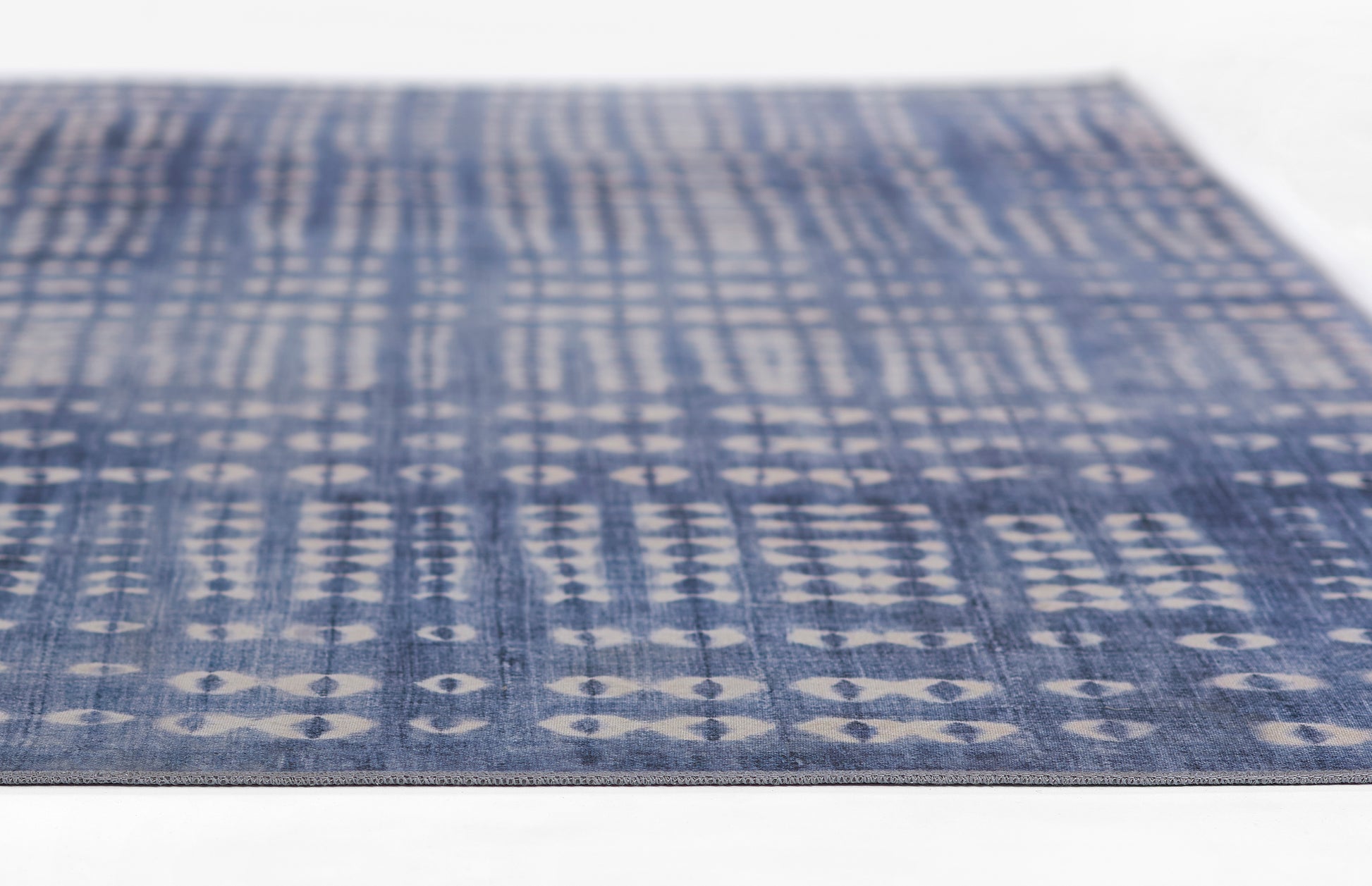 Blue flat-weave rug with white diamond grid pattern; rectangular, modern casual decor.