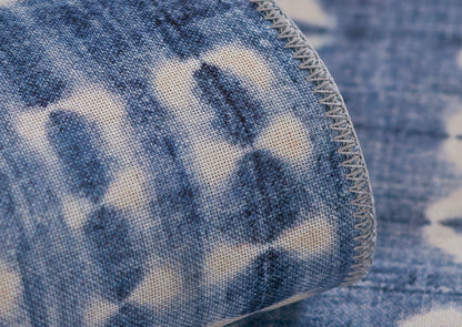 Close-up of blue and white tie-dye rug with grey overlock stitching along the edge