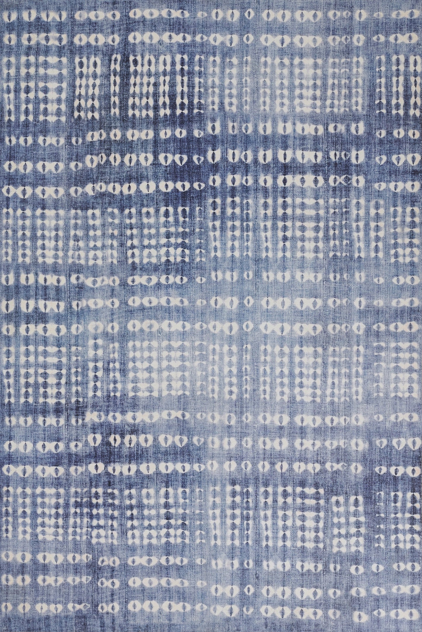 Blue woven rug with white dotted grid pattern; geometric, tie-dye style print.
