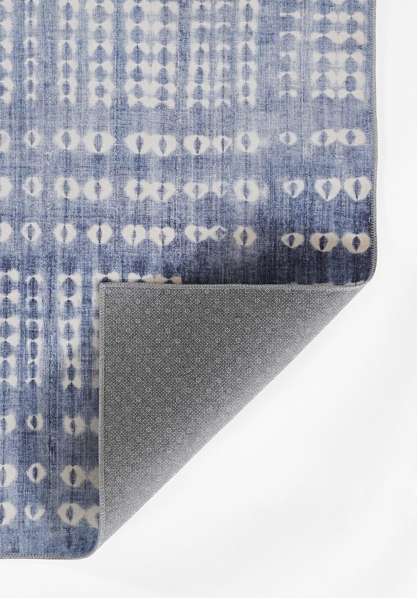 Blue rug with white circular geometric pattern in vertical rows; folded corner reveals gray speckled underside.