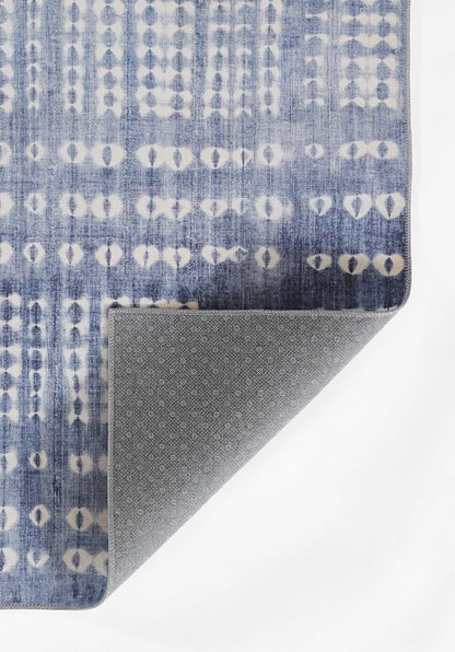 Blue rug with white circular geometric pattern in vertical rows; folded corner reveals gray speckled underside.