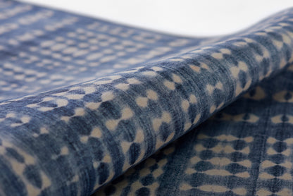 Blue denim-inspired rug with beige speckle pattern, close-up of folded rug