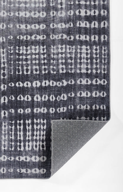 Dark navy rug with white circular dot lattice pattern; woven texture, corner folded to reveal gray non-slip underside.