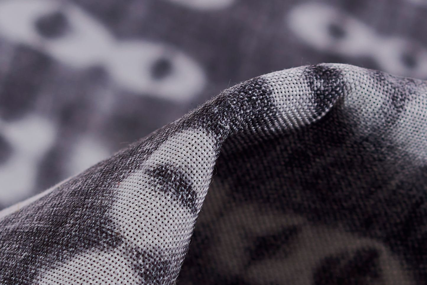 Close-up of a grey and black patterned rug with a woven texture and folded edge.