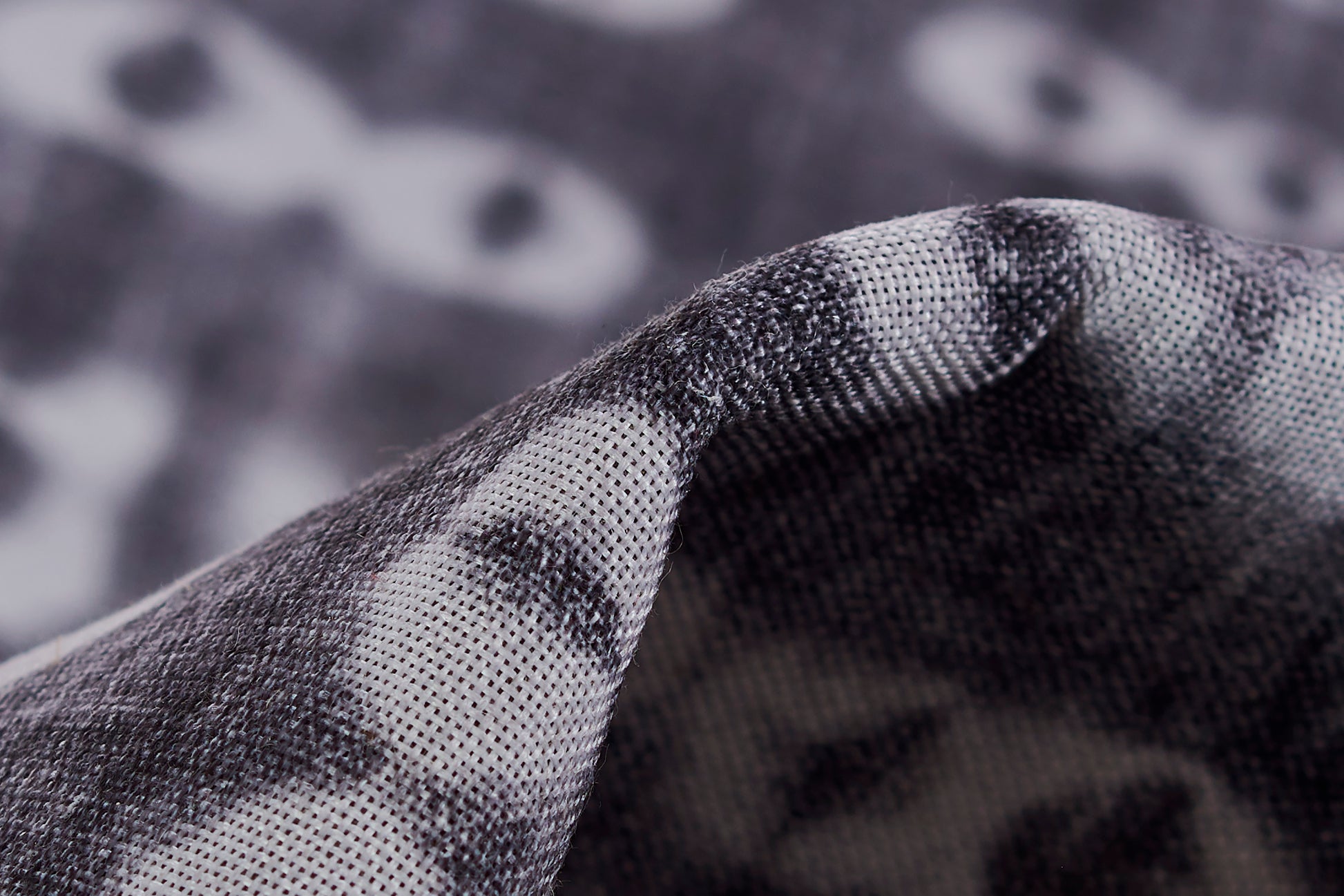 Close-up of a grey and black patterned rug with a woven texture and folded edge.