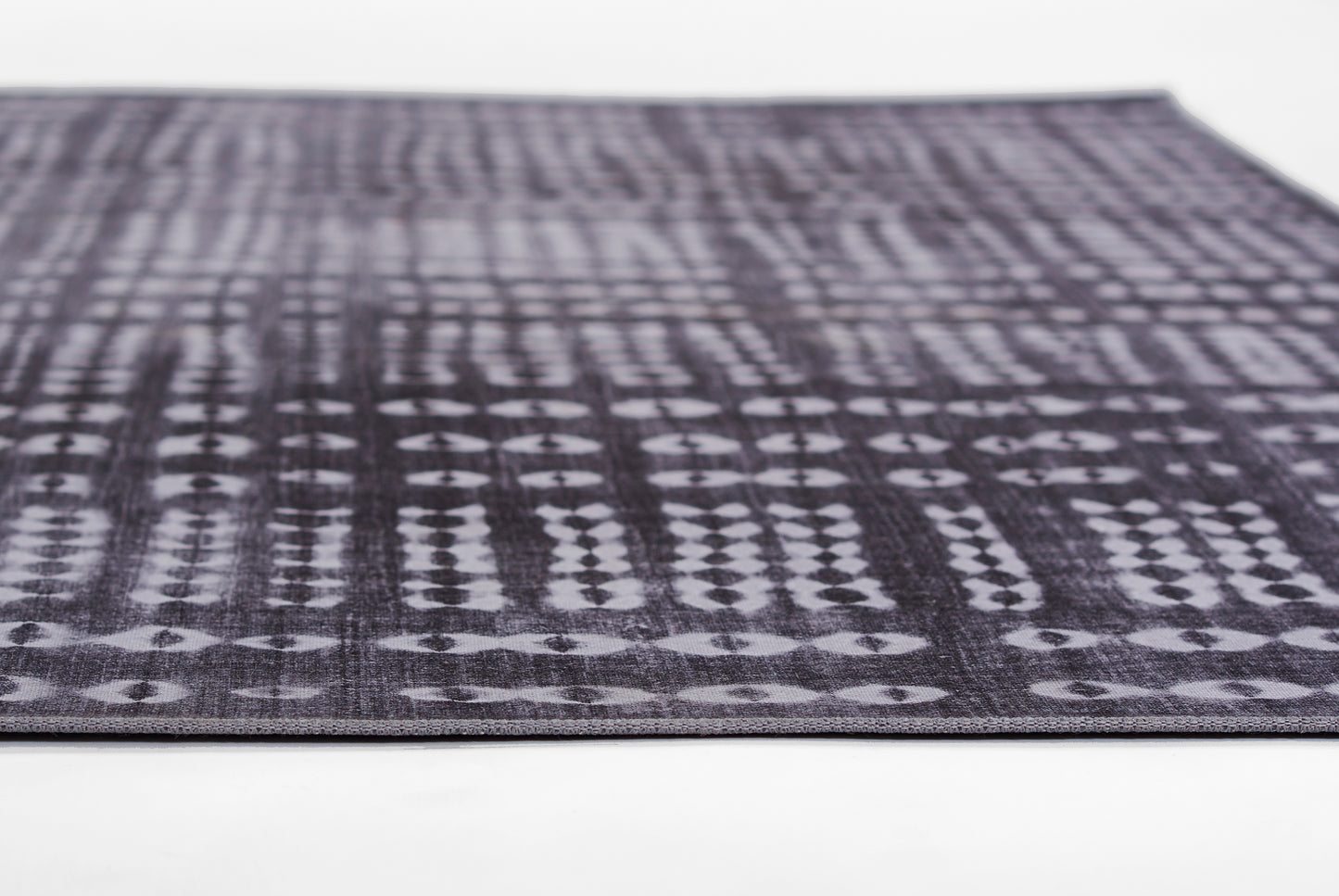 Dark purple woven rug with light gray geometric diamond pattern; low-pile, rectangular area rug.