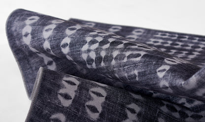 Dark indigo woven fabric with pale gray irregular spots, folded textile suitable as scarf or throw.