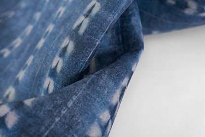 Close-up of blue denim fabric with white ikat print and a folded edge.