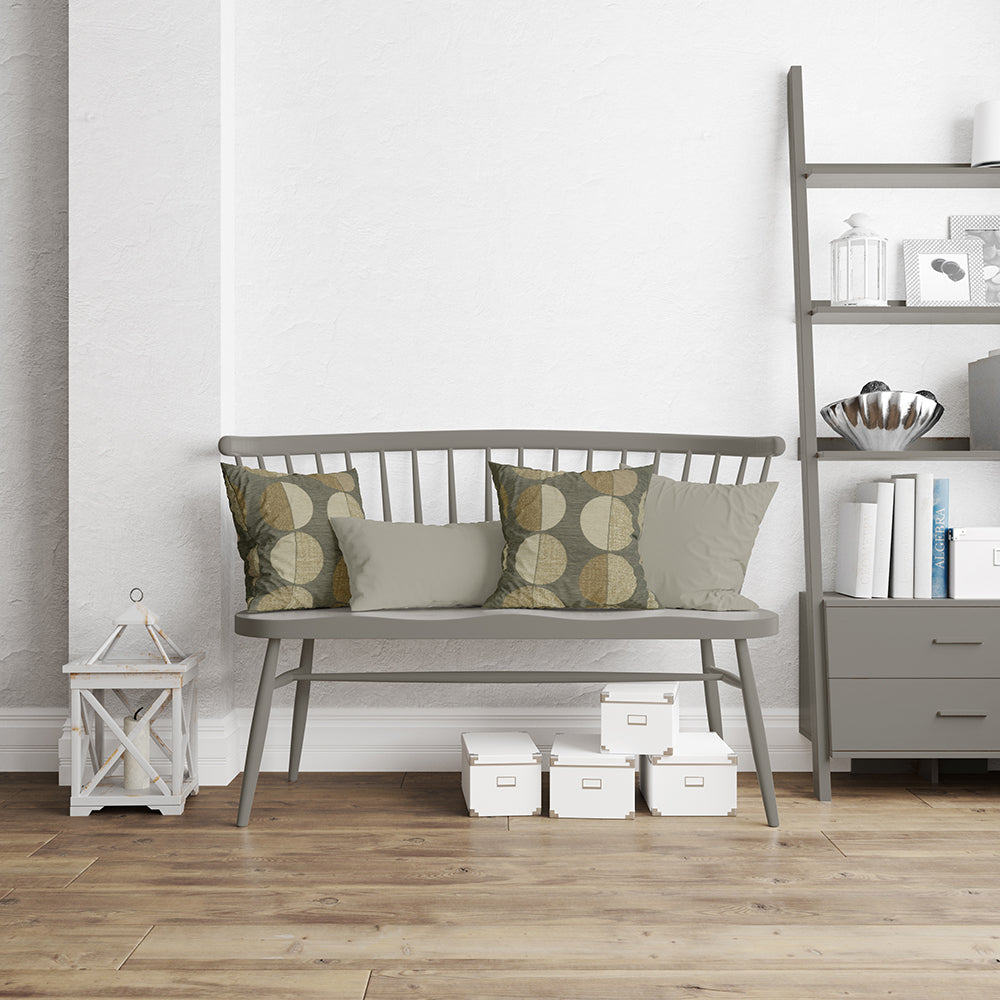 Gray seating upholstered in oxide geometric fabric NJ25-376 with olive patterned cushions, in a living room with a shelf and a lantern.