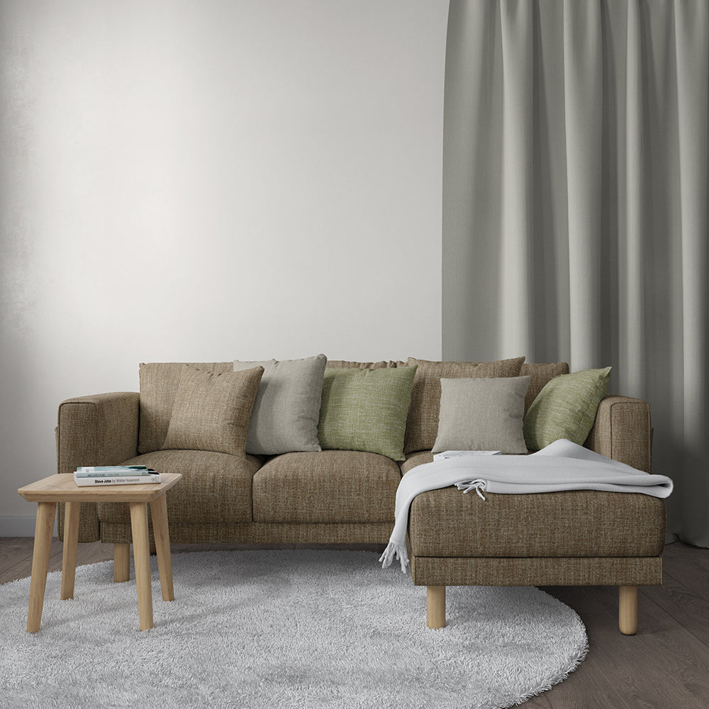 Brown fabric upholstery on a sectional with chaise, beige/green/grey cushions, light wood legs; throw blanket, round wood table, gray rug