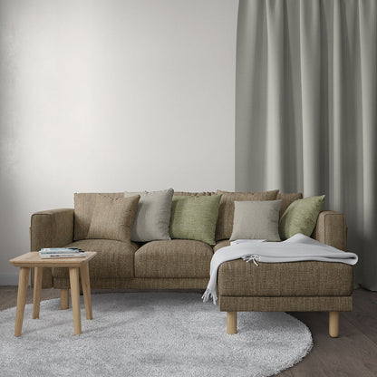 Brown fabric upholstery on a sectional with chaise, beige/green/grey cushions, light wood legs; throw blanket, round wood table, gray rug
