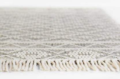 Cream boucle rug with a subtle gray geometric pattern and thick twisted fringe along the edge.