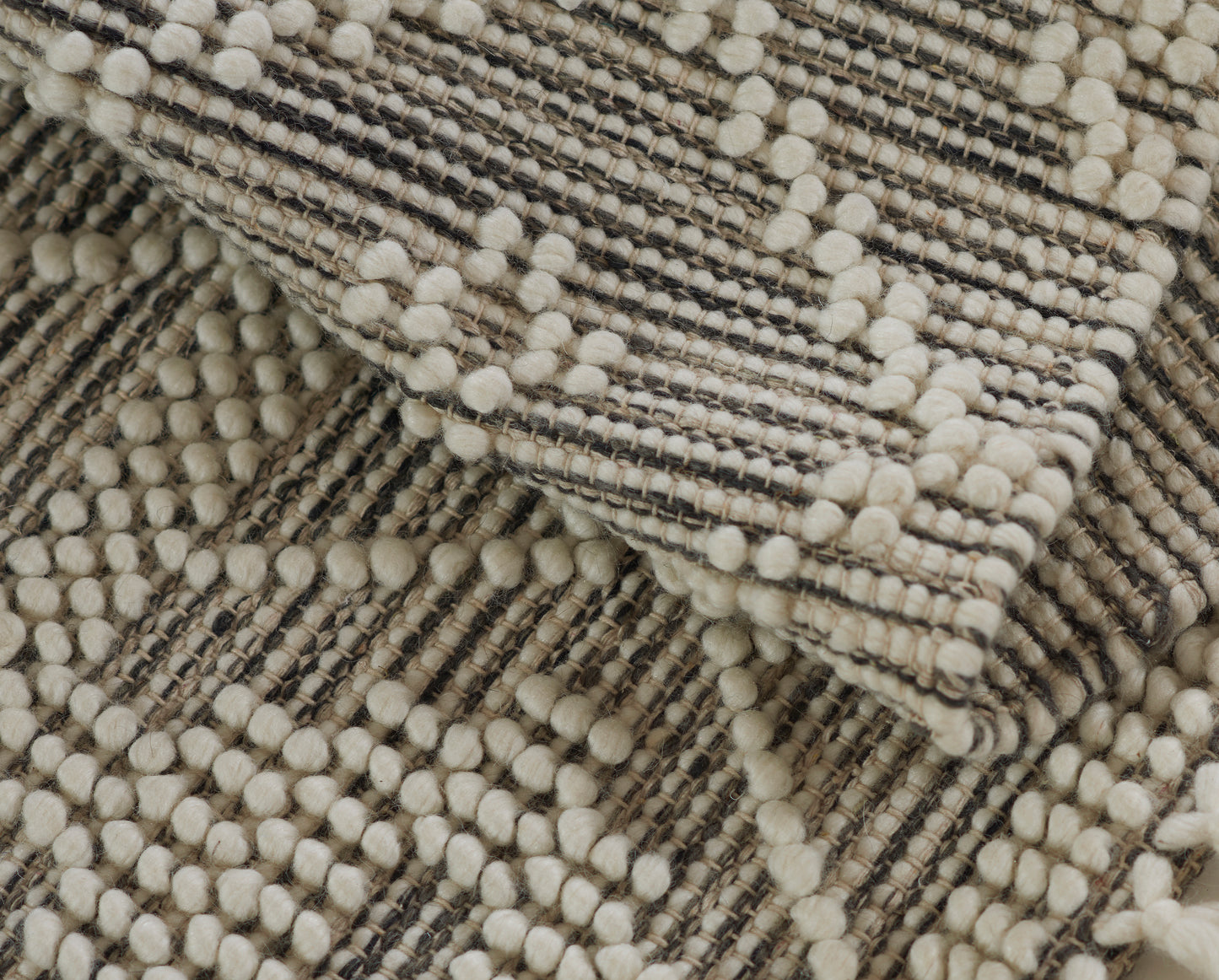 Cream and beige chunky woven rug runner with striped texture and pom-pom edging, 2' x 8'.