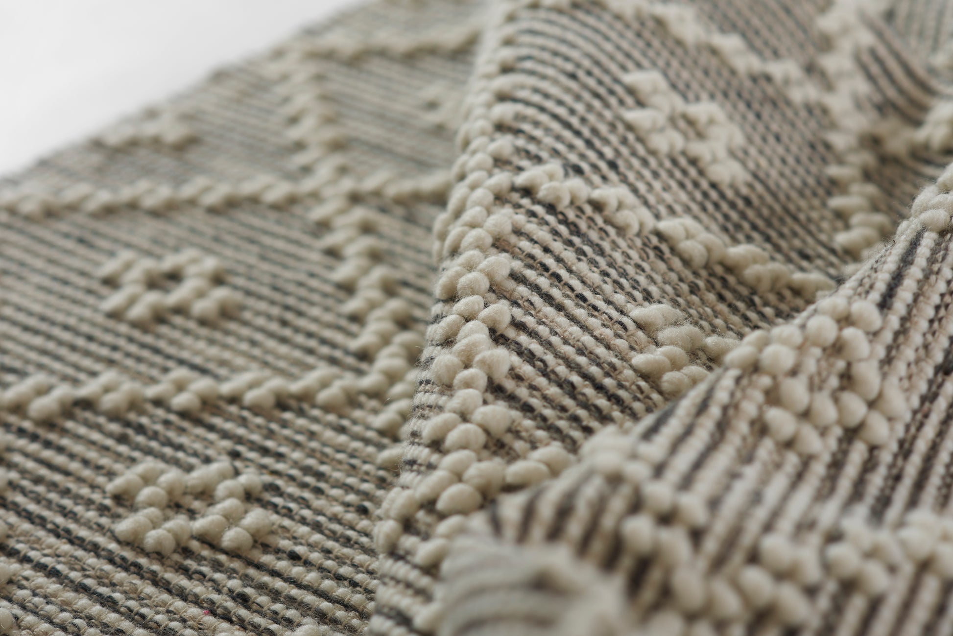 Beige bouclé woven rug with raised cream loop texture and striped pattern; soft neutral floor decor.
