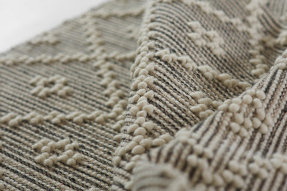 Cream taupe boucle rug with chunky loops and raised pom-pom texture, striped geometric weave for a cozy floor.