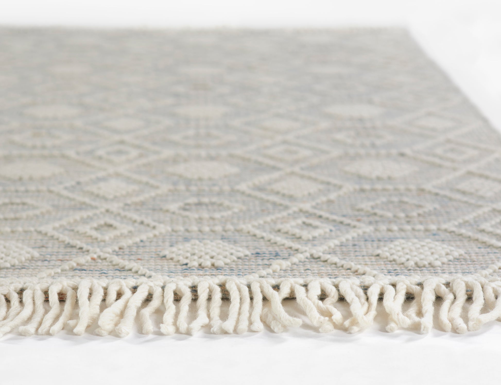 Light gray and ivory geometric diamond runner rug with cream fringe along edge, 2' x 8'.