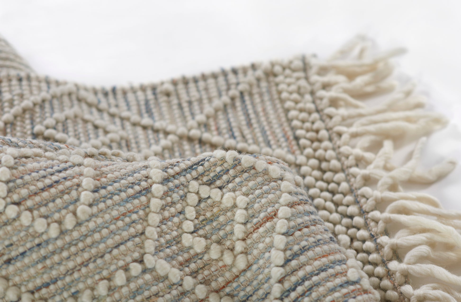 Neutral woven rug with raised bobble texture and fringed edges in cream, beige and pale blue, 8' x 10