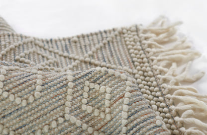 Cream-beige woven throw with bobble textures and fringed tassels, boho-style home rug decor.