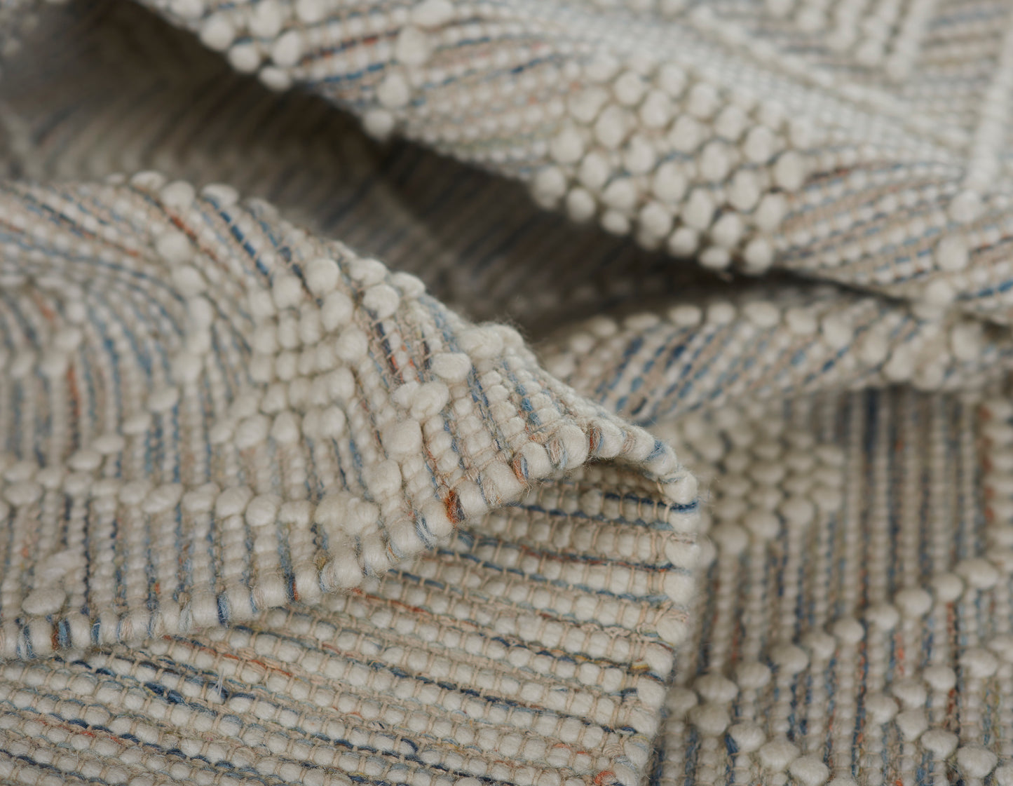 Cream boucle woven rug, 2' x 3', with chunky bobble fringe and subtle blue and tan stripes.