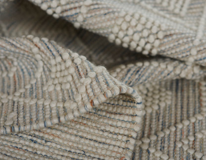Cream boucle textile with looped yarn and pale blue and brown flecks; cozy woven throw rug.