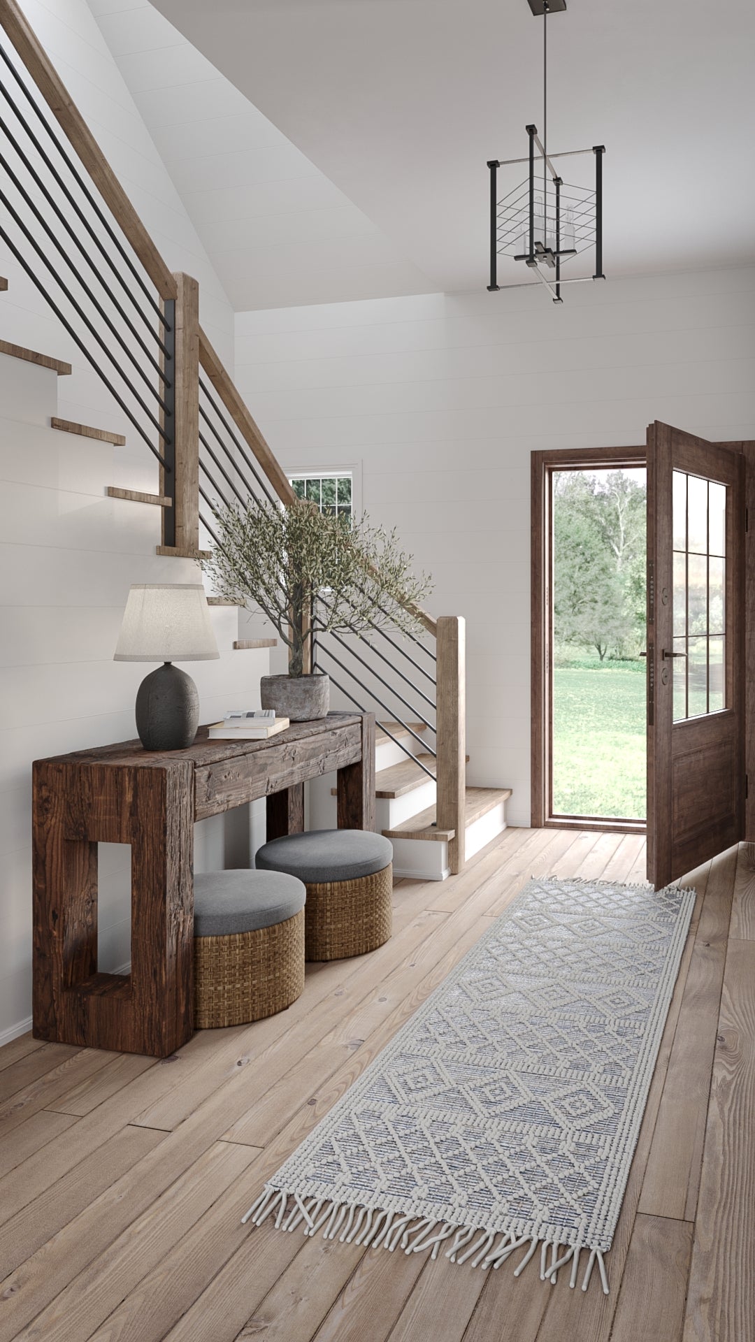 Rustic entryway with a chunky wood console, two wicker stools with gray cushions, potted greenery, geometric rug, open door.