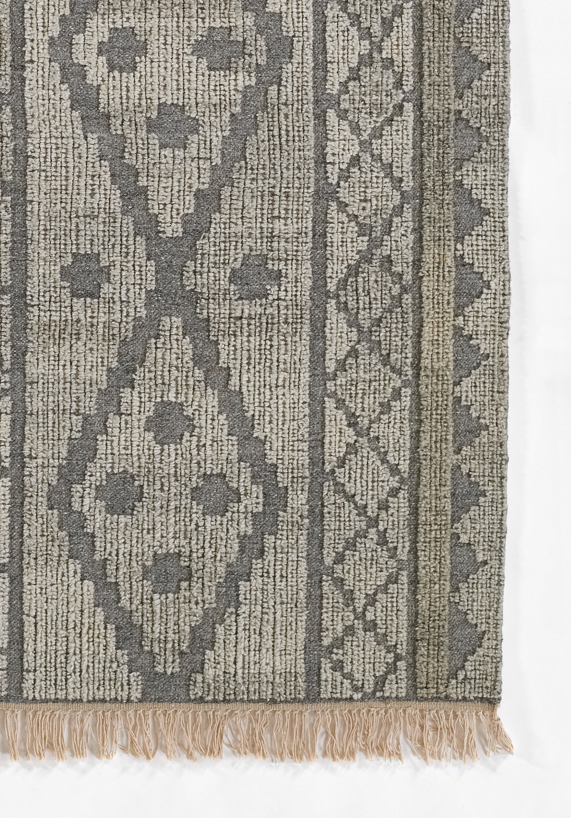 Woven rug in grey and beige tones with a large diamond motif, tribal border, and beige fringe.
