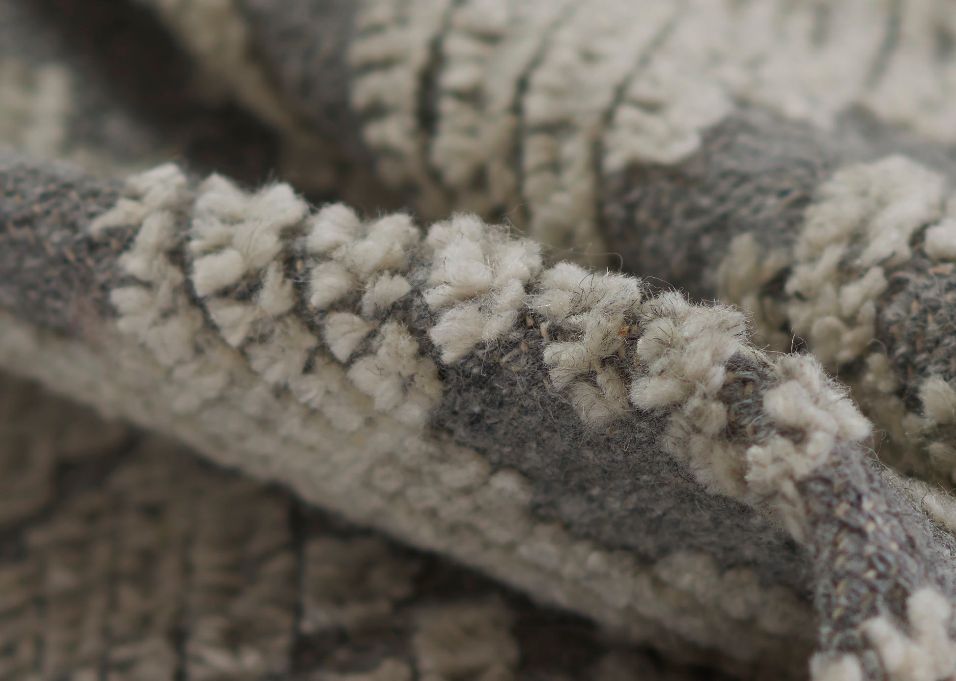 Close-up of grey & ivory fluffy boucle knit with chunky loops, a cozy throw blanket texture.
