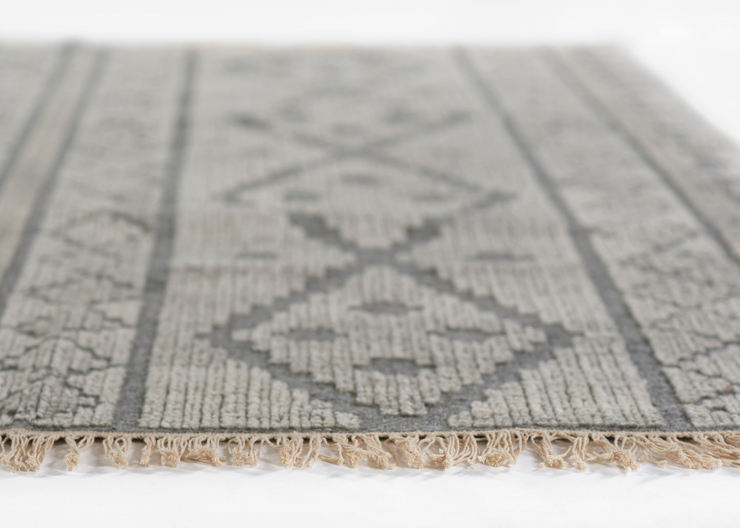 Gray geometric woven rug with diamond pattern and beige tassel fringe along the edge.