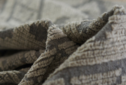 Close-up of soft gray and beige woven rug fabric with plush loop pile.