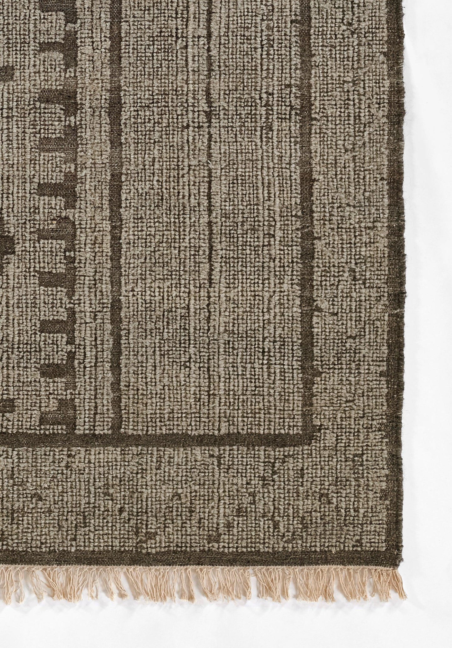Natural fiber rug in tan and dark brown with a bold border, subtle vertical weave, fringed edge.