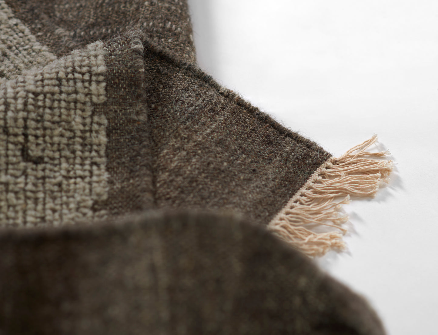 Brown woven scarf with beige fringe and a subtle geometric pattern; chunky textured weave.