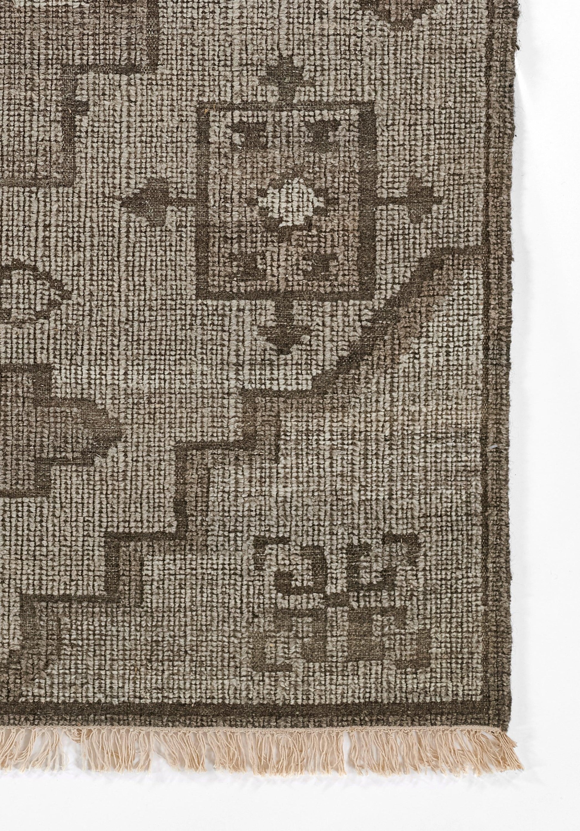 Natural brown woven rug with geometric border and centered square motif, fringed edge for rustic home decor.
