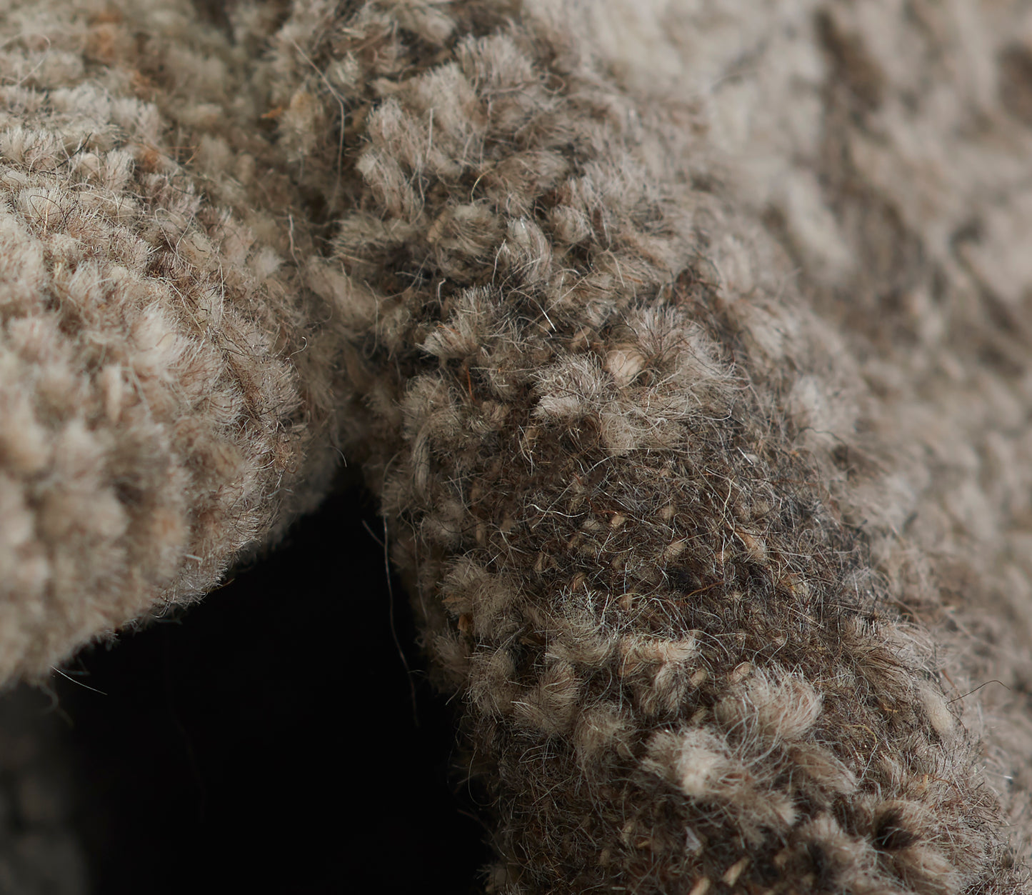 Close-up of a beige-brown shaggy rug texture with plush, fluffy fibers and natural, variegated tones.