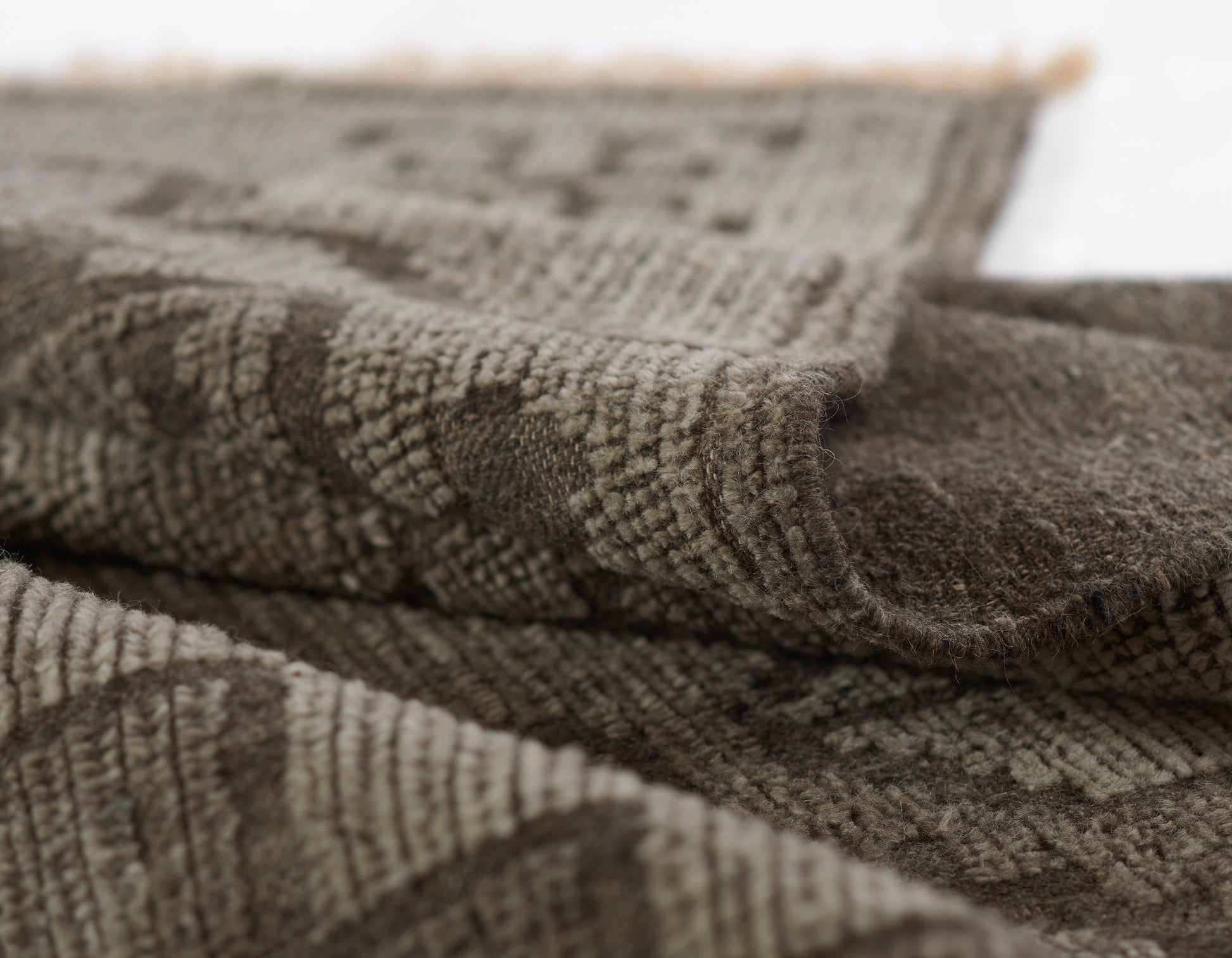 Brown and beige woven rug with fringed edge, soft textured pile, rustic geometric pattern.