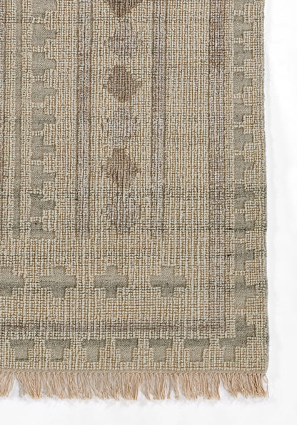 Beige-taupe woven rug with geometric diamond motifs, vertical stripe texture & fringe tassels along the bottom edge.