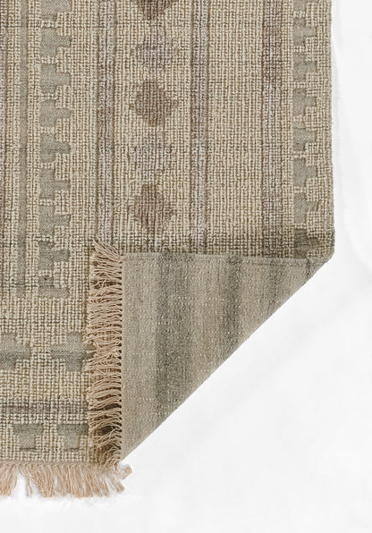 Beige and taupe woven rug with geometric stripe pattern, fringe tassels on one edge, folded corner showing underside.