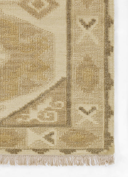 Beige woven rug corner with taupe border, fringe, and geometric motifs for neutral decor.