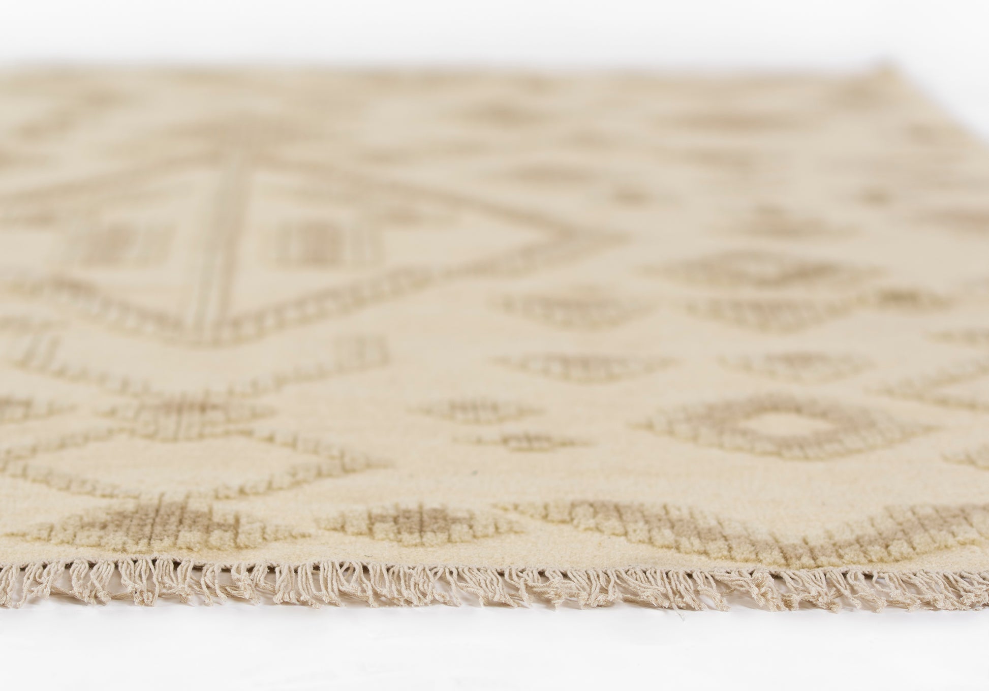 Natural beige flat-weave rug with subtle taupe geometric pattern and fringed edge.