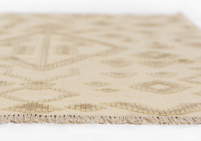 Beige natural woven rug with subtle diamond geometric pattern and fringe along edge.