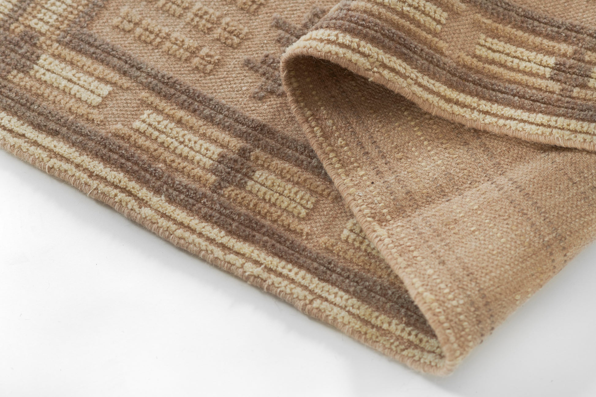Beige and brown striped rug with geometric motif and soft plush pile, folded corner.
