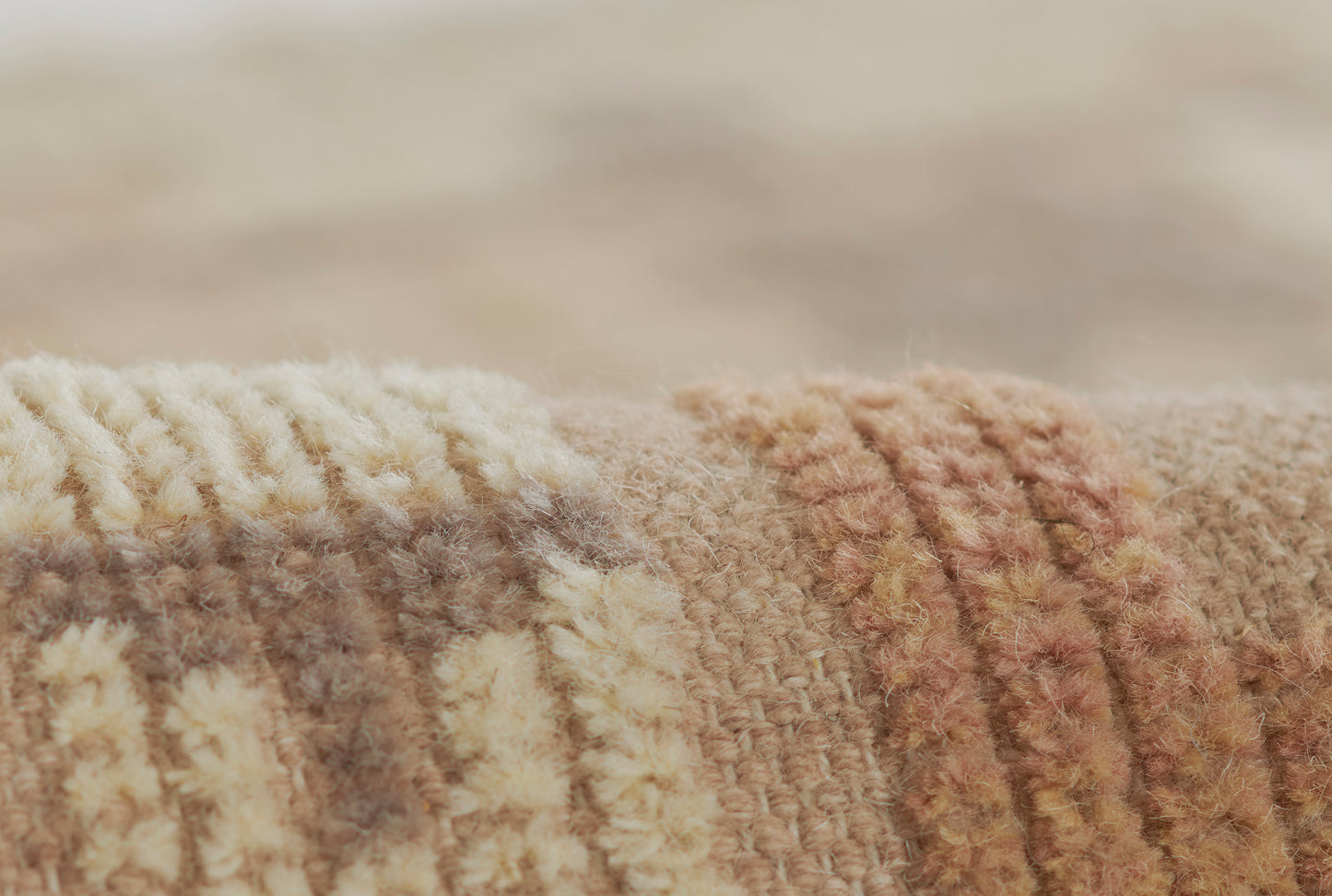 Close-up of a soft, textured striped rug in cream, beige and brown tones with a plush woven pile.