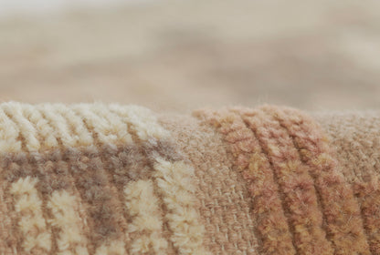 Close-up of a plush beige, cream and tan striped blanket with thick yarn and fuzzy pile.