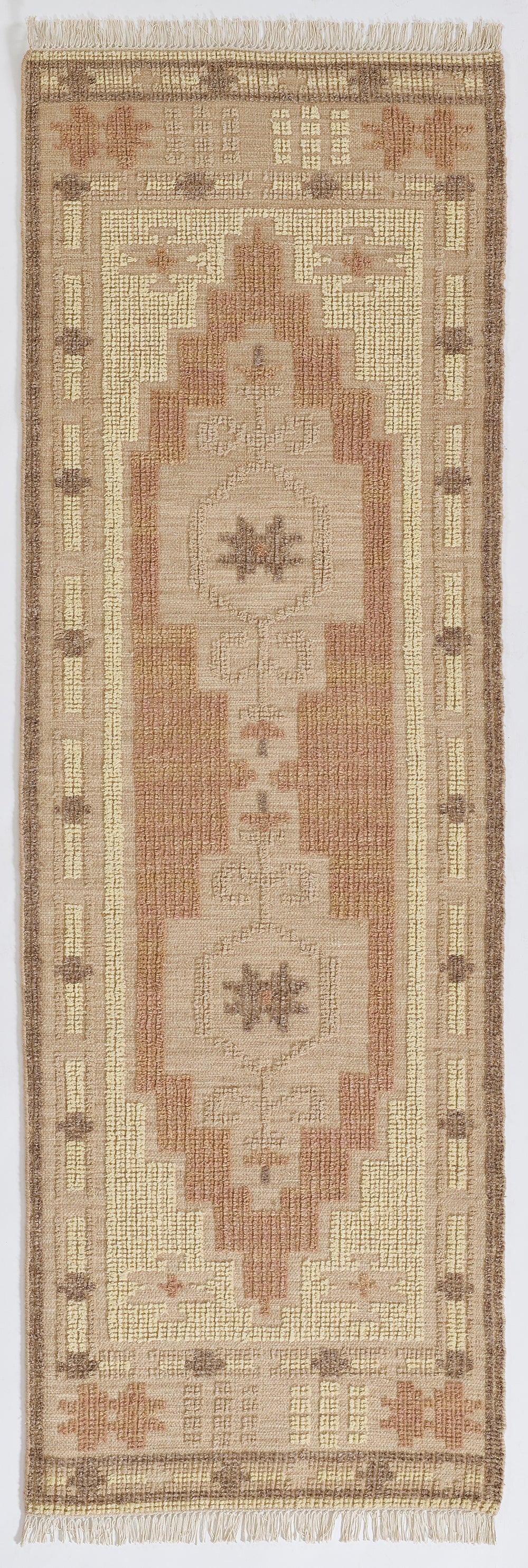Woven runner rug in beige, tan and rose with geometric stepped medallions, cream border, fringed ends.