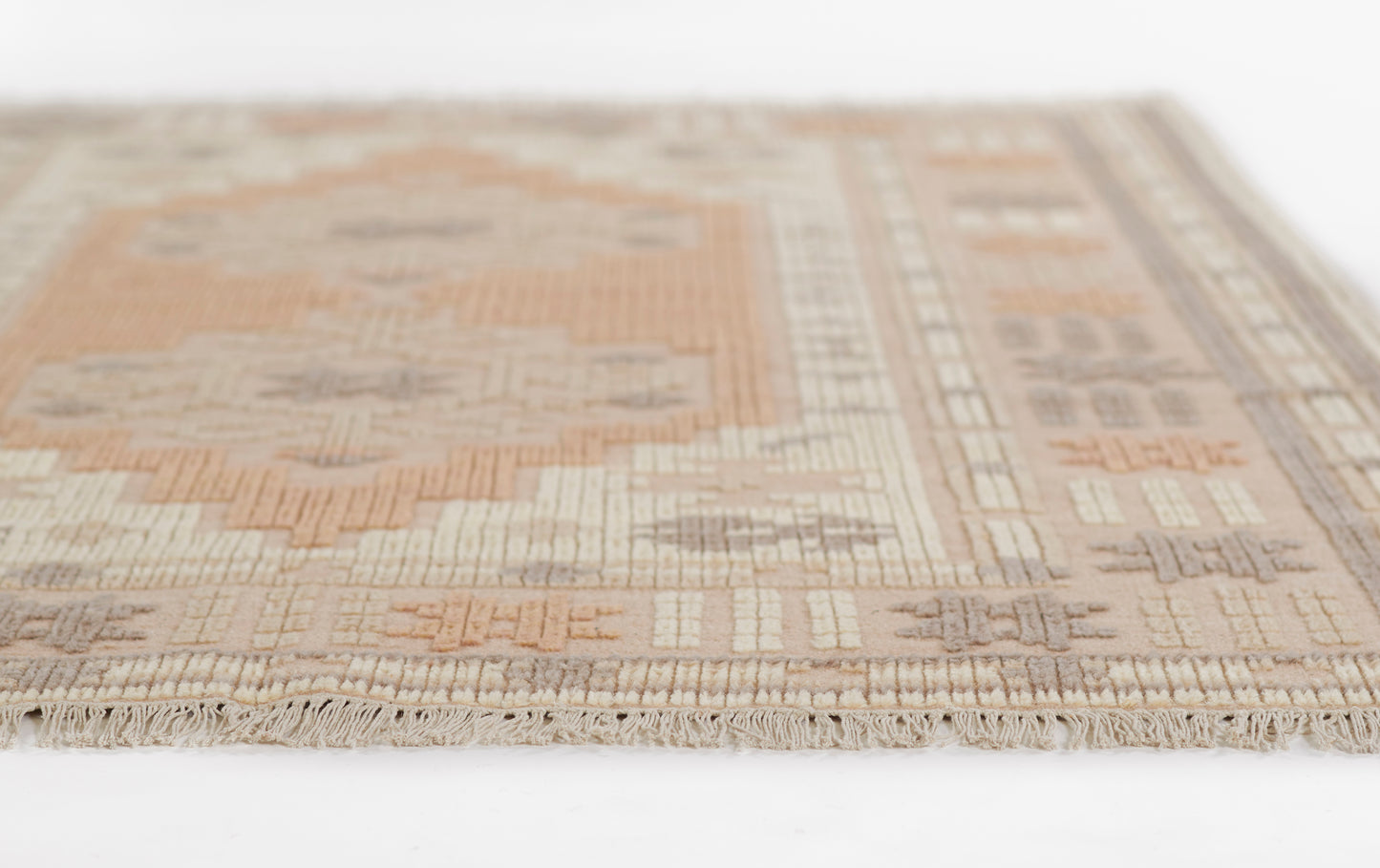 Beige, tan and peach geometric rug with woven texture and fringed edges.